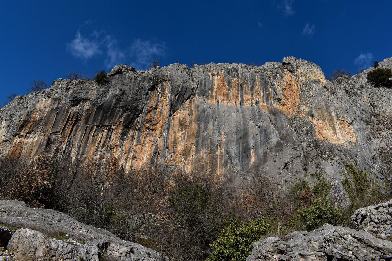 Pared de caliza vertical con vetas grises y ocres bajo cielo despejado, el tipo de roca que se escala en Potrero Chico