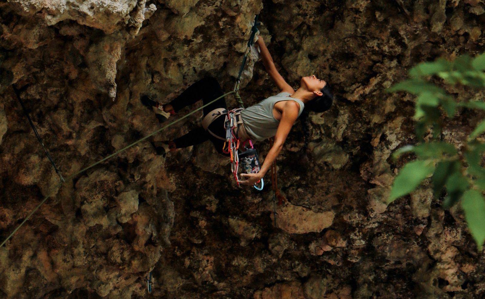 Escaladora en una pared de caliza erosionada con la magnesiera colgada del arnés